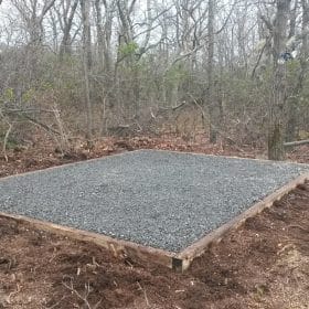 Gravel shed foundation installed in woods