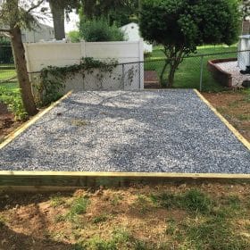 A gravel shed pad installation with a wood perimeter