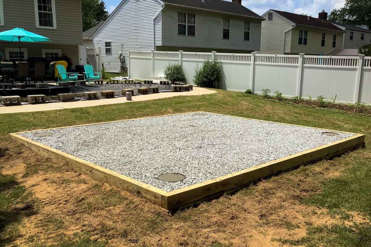 A shed pad made from crushed stone with concrete pier footers in the corners