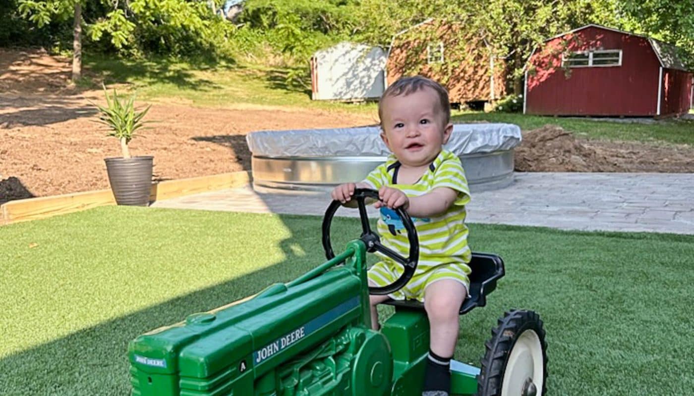 exterior of artificial turf foundation with kid on tractor
