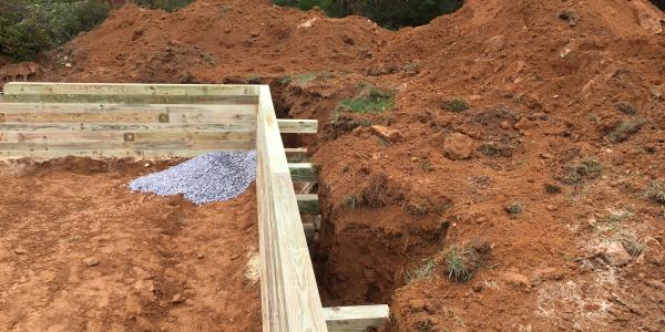 Bracing for a wood retaining wall on a gravel garage foundation installation